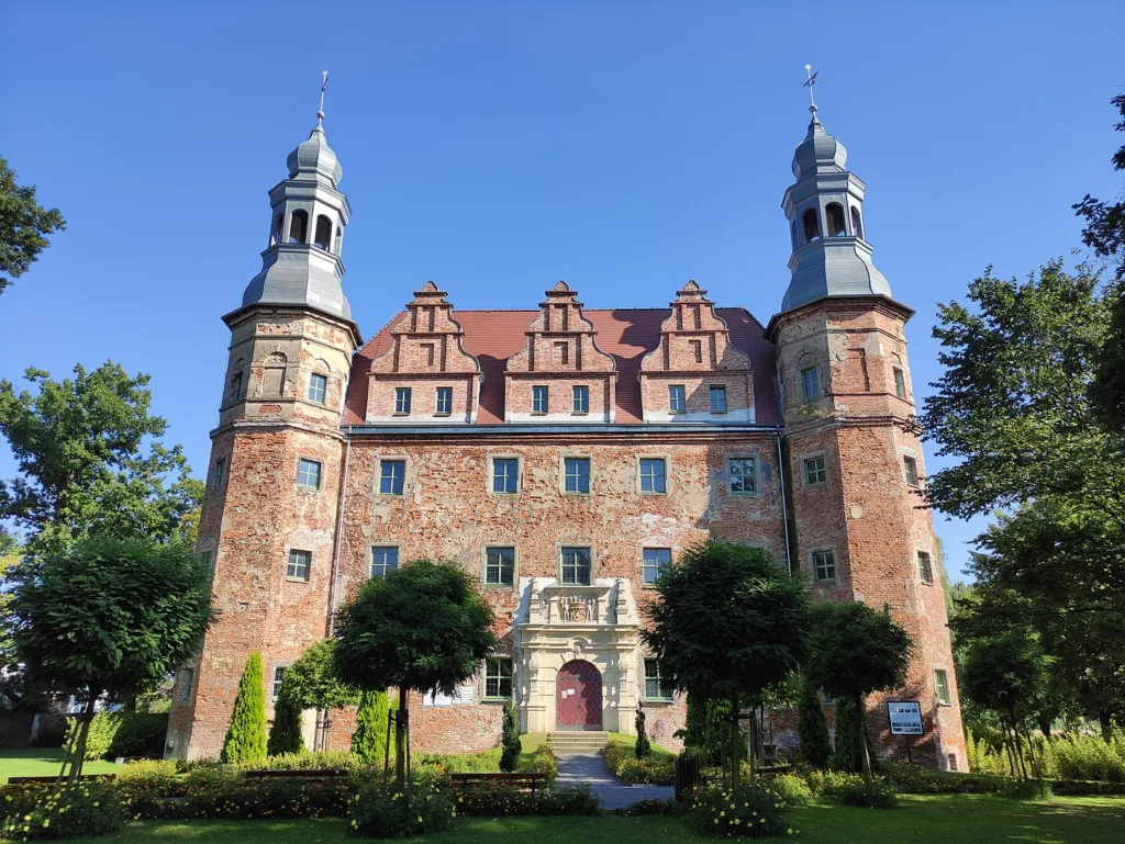 Strzelisty pałac od frontu w otoczeniu zieleni.