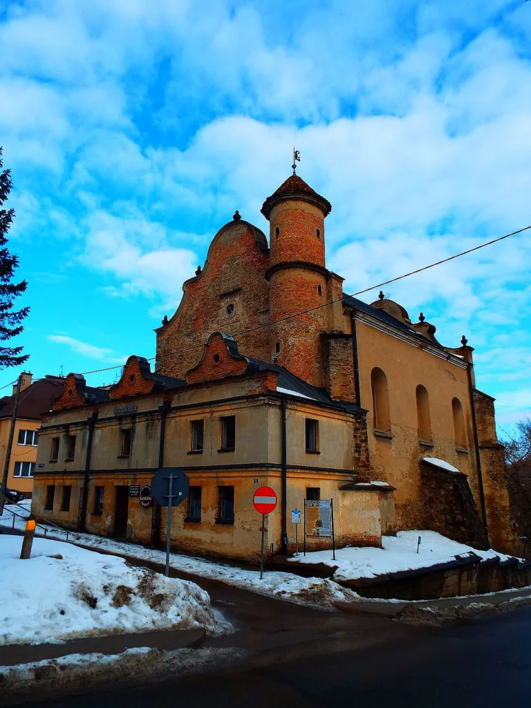 Zdjęcie przedstawia synagogę - murowany budynek z oknami i wieżyczkami.