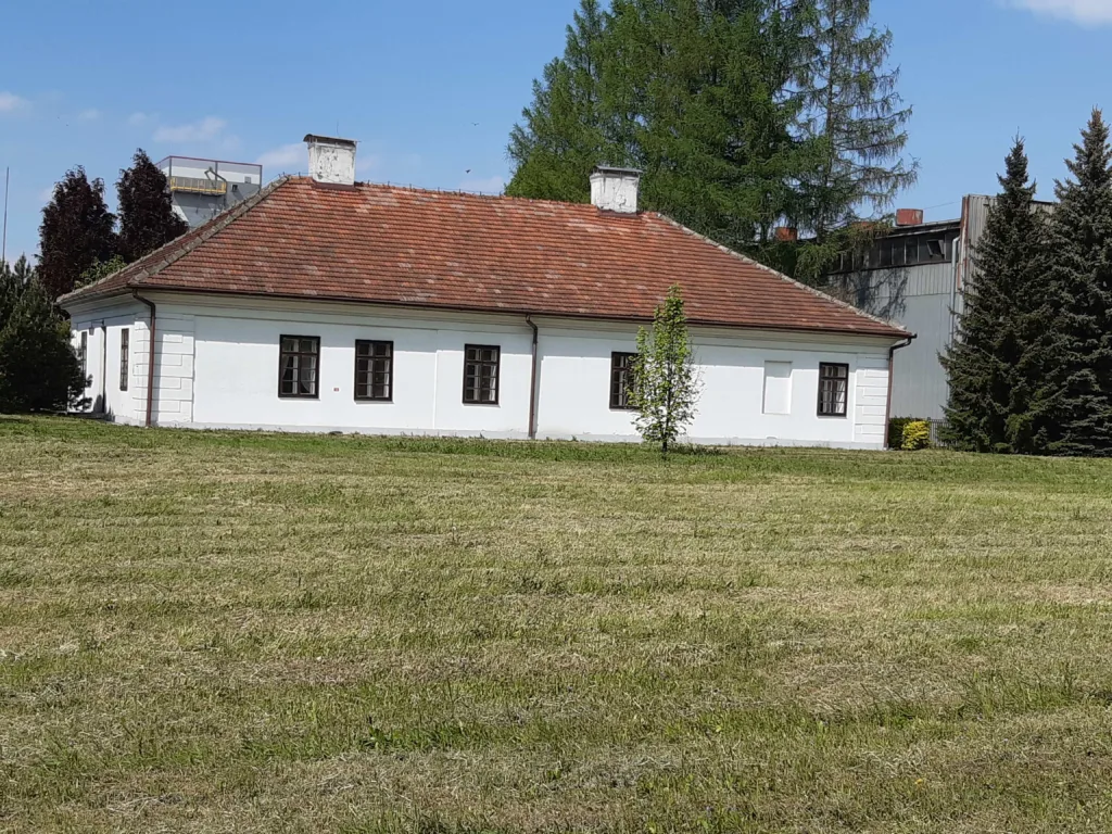 Biały, parterowy budynek z czerwonym dachem.
