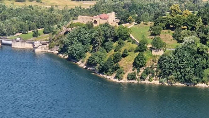 Zdjęcie: widok z lotu ptaka na zamek w otoczeniu rozległej zieleni. W pobliżu woda.