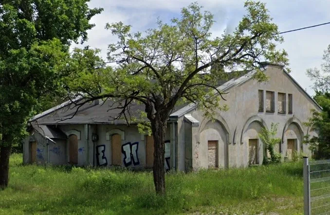 Widok budynku z zewnątrz, pośród zieleni.
